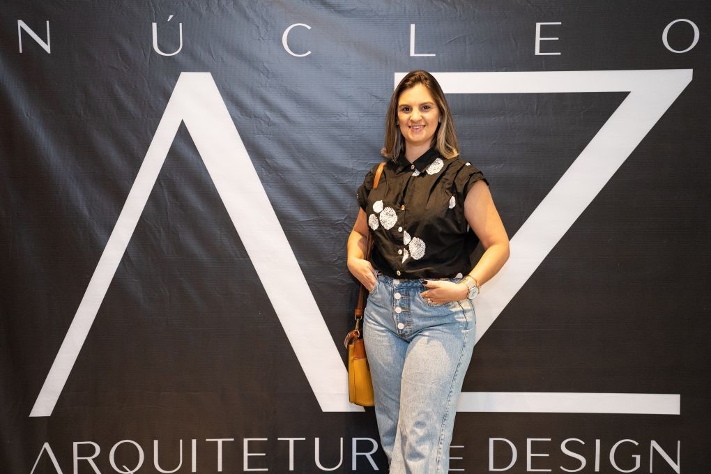 Uma mulher está em frente a uma placa que diz nucleo arquitetura design