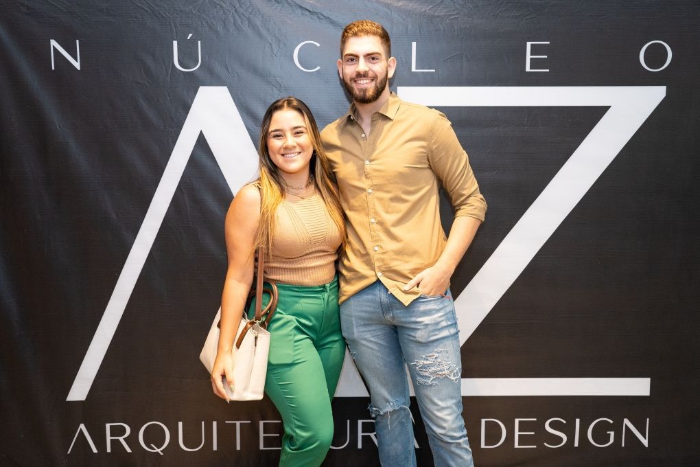 Um homem e uma mulher estão posando para uma foto em frente a uma placa que diz nucleo