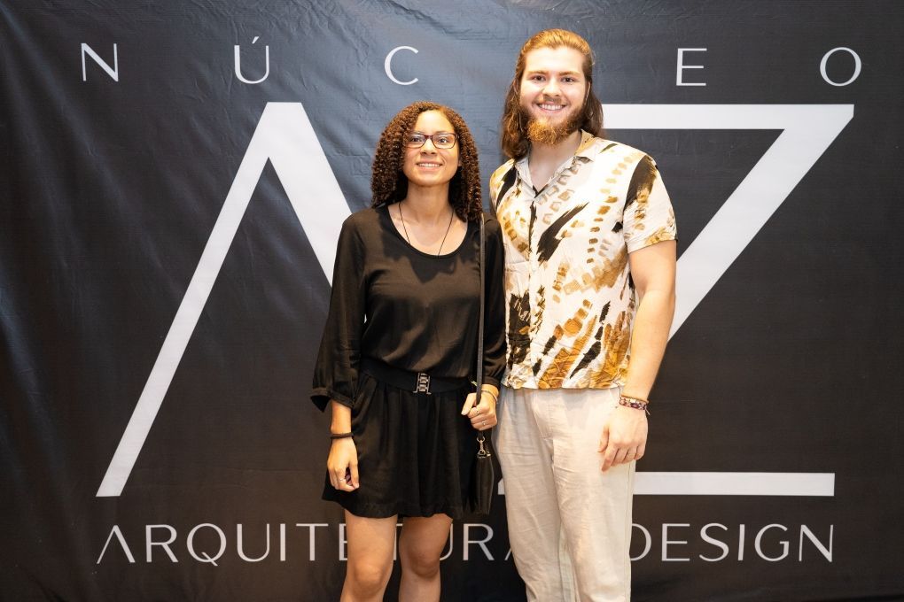 Um homem e uma mulher estão parados em frente a uma placa que diz arquitetura design