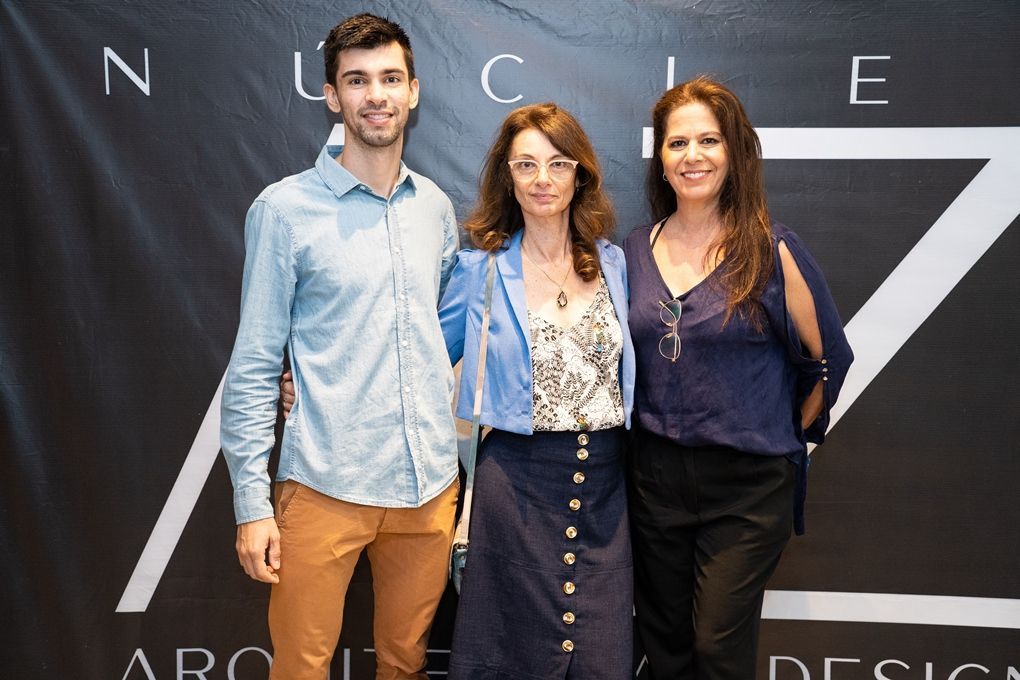 Um homem e duas mulheres estão posando para uma foto em frente a um fundo preto.