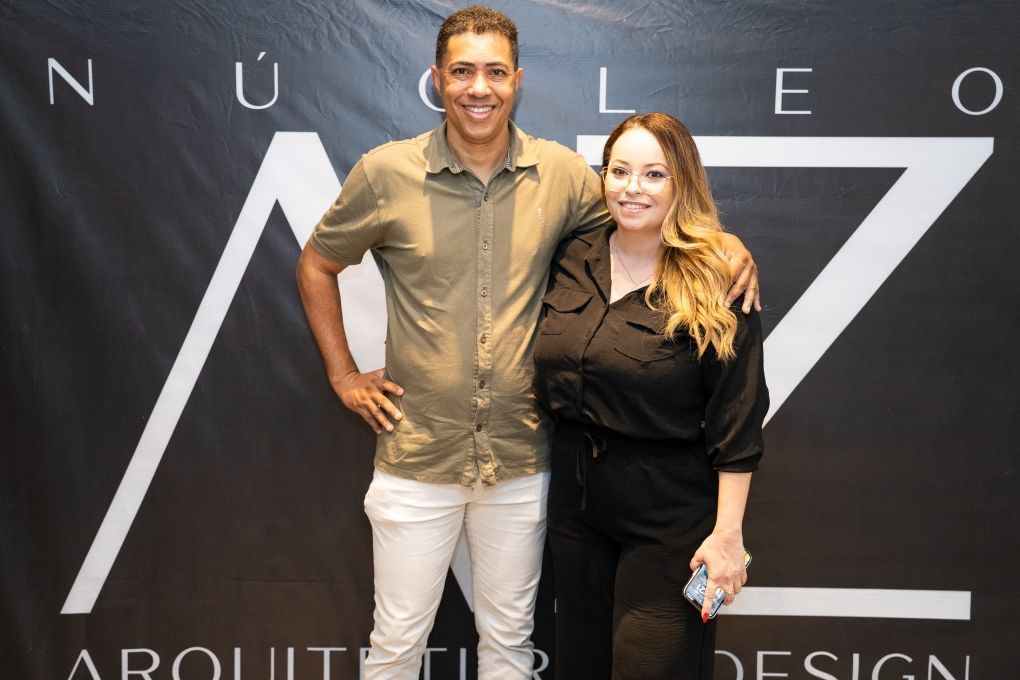 Um homem e uma mulher posam para uma foto em frente a uma placa que diz arquitetura design