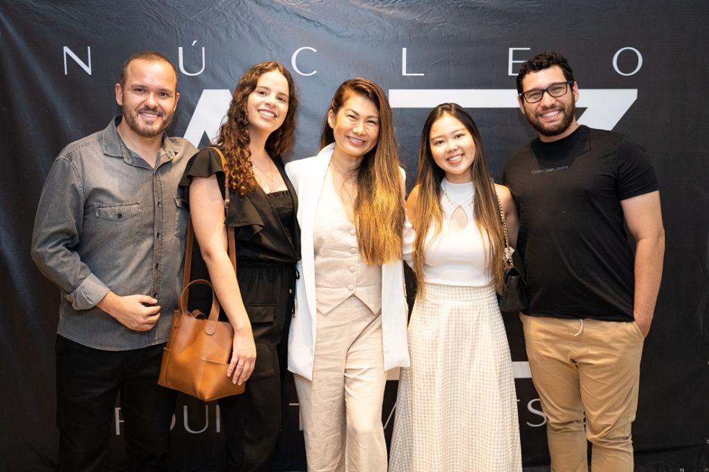 Um grupo de pessoas está posando para uma foto em frente a uma placa que diz nucleo.