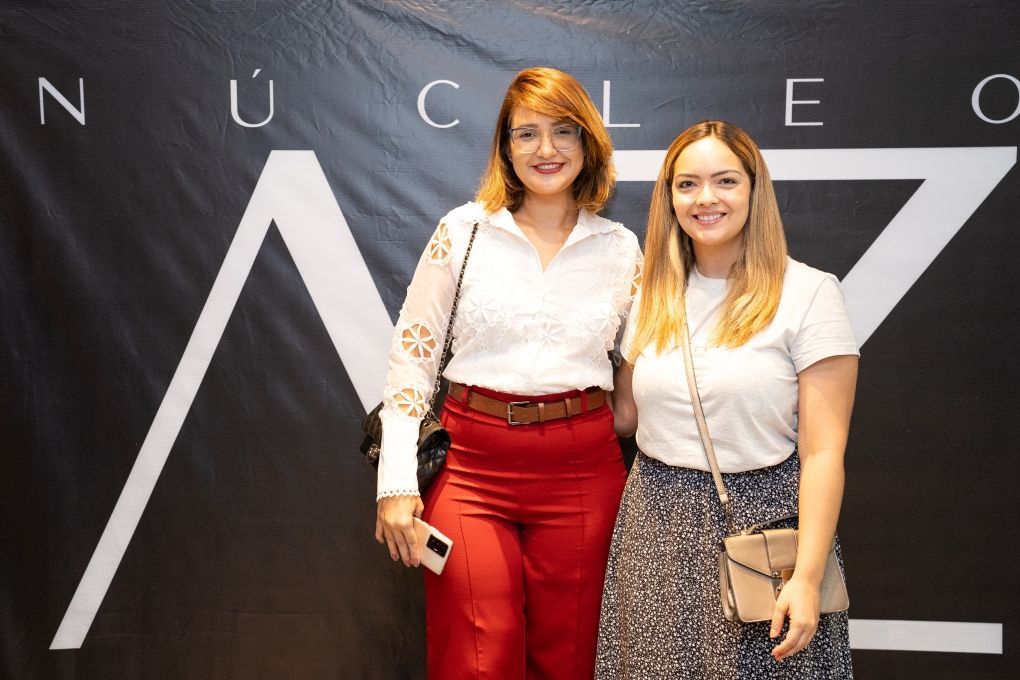 Duas mulheres posam para uma foto em frente a uma placa que diz núcleos
