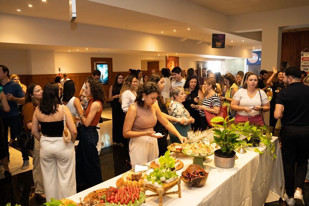 Um grupo de pessoas está em pé ao redor de uma mesa de bufê.