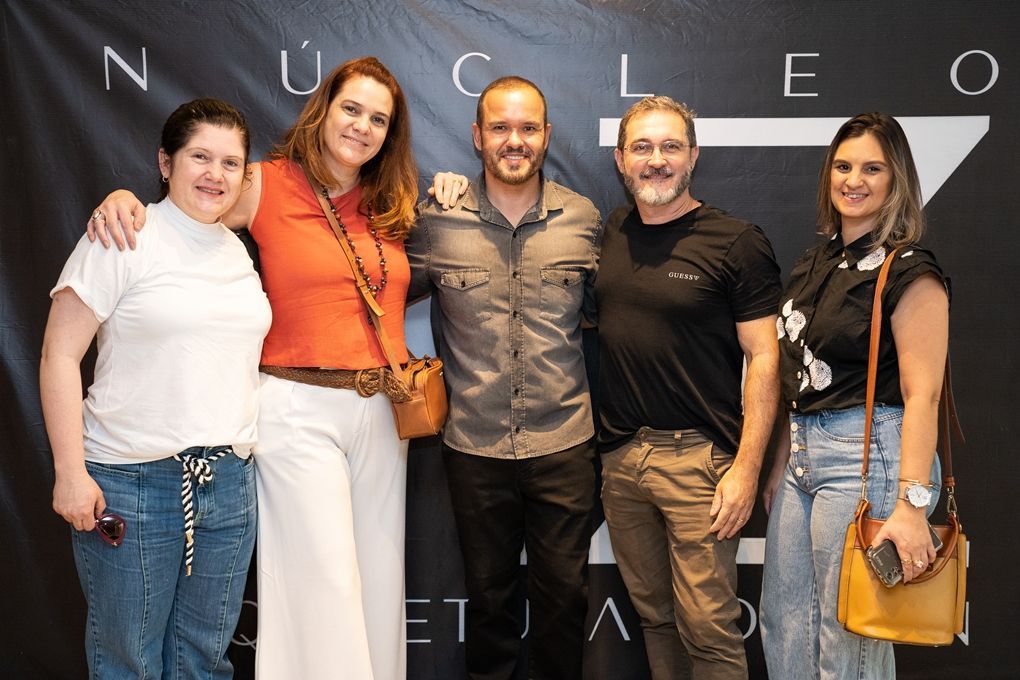 Um grupo de pessoas está posando para uma foto em frente a um fundo preto.