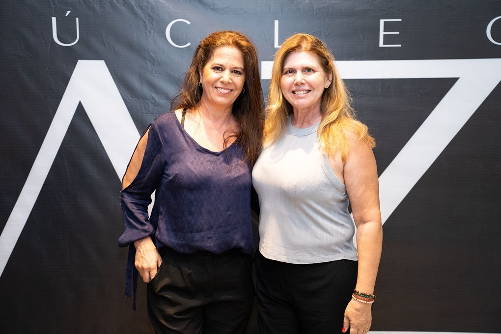 Duas mulheres estão posando para uma foto em frente a uma placa que diz ucl