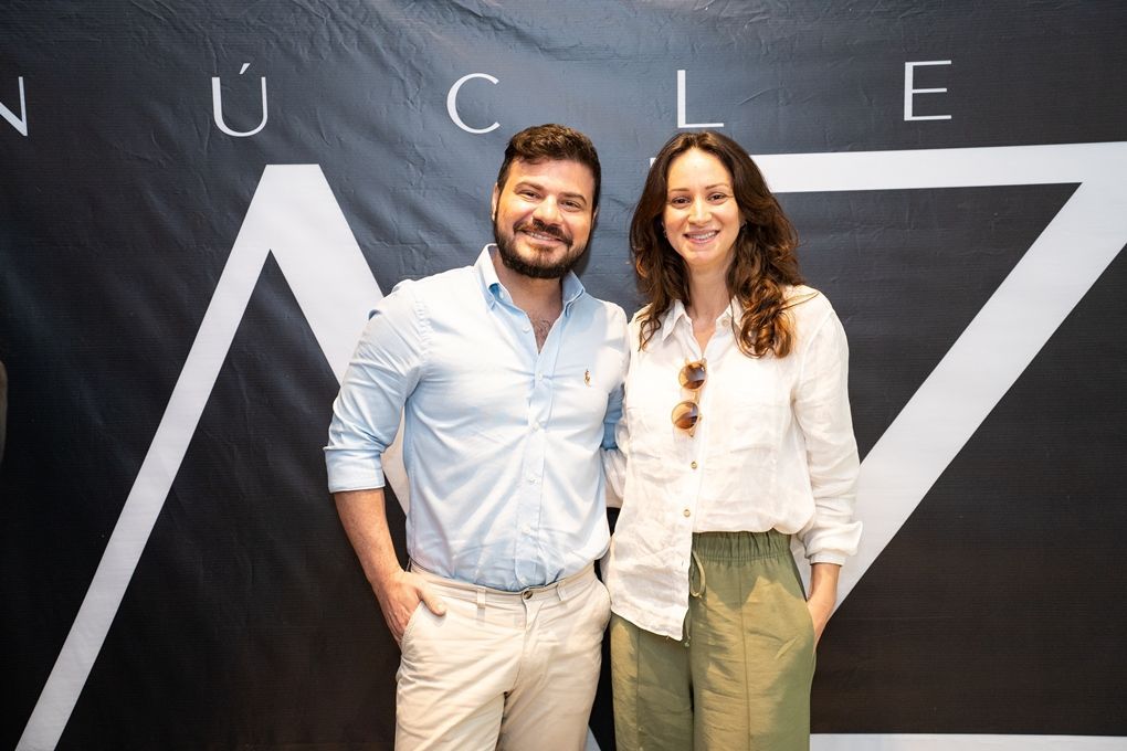 Um homem e uma mulher estão posando para uma foto em frente a uma placa.