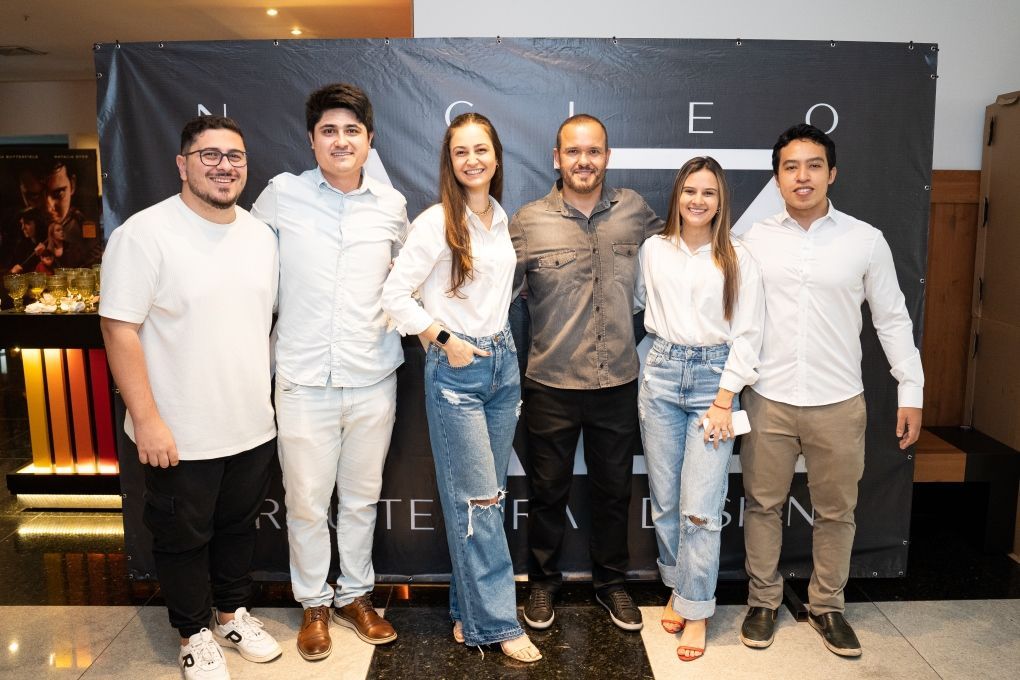 Um grupo de pessoas está posando para uma foto em frente a um banner.
