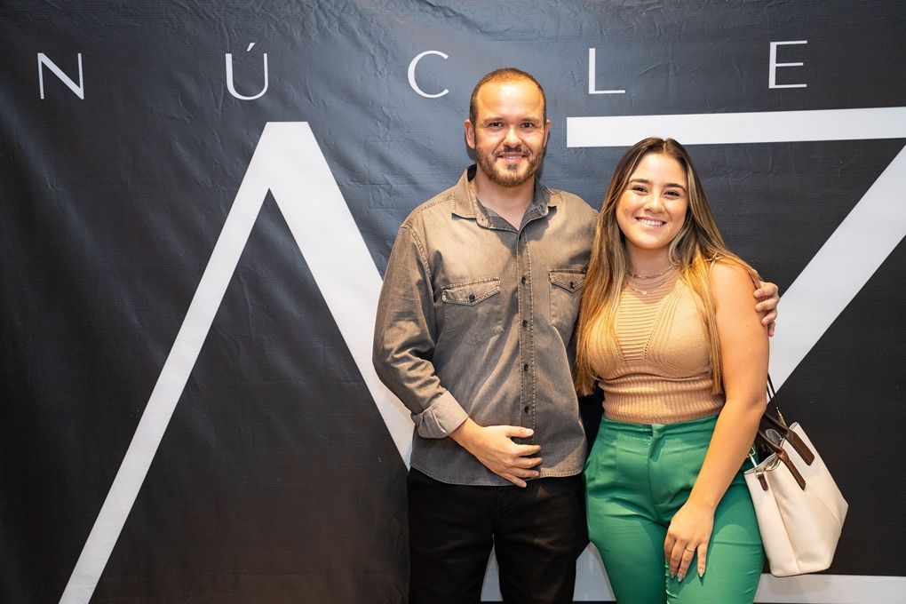 Um homem e uma mulher estão posando para uma foto em frente a uma placa.