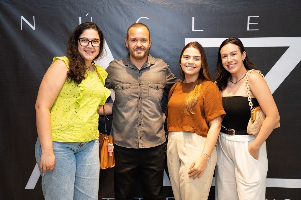 Um grupo de pessoas posando para uma foto em frente a uma placa que diz z