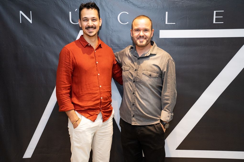 Dois homens estão posando para uma foto em frente a uma placa que diz nuclear