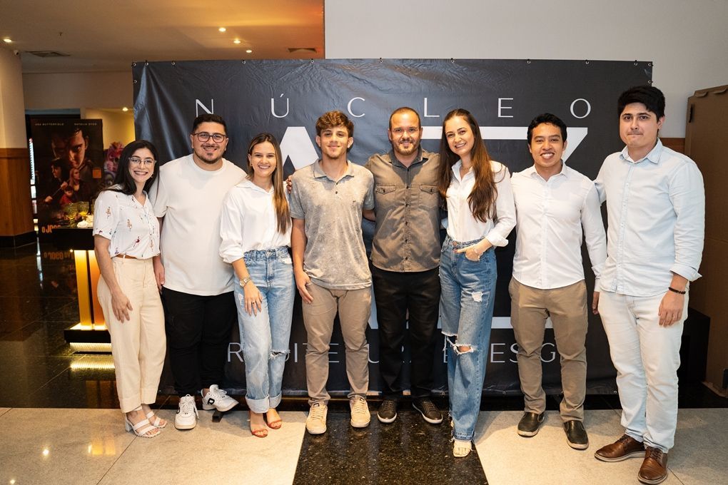 Um grupo de pessoas está posando para uma foto em frente a um banner.