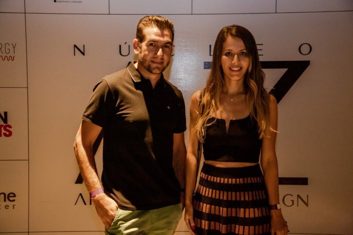 Um homem e uma mulher estão de pé, um ao lado do outro, em frente a uma parede.
