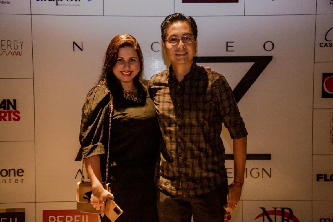 Um homem e uma mulher estão posando para uma foto em frente a uma parede com logotipos
