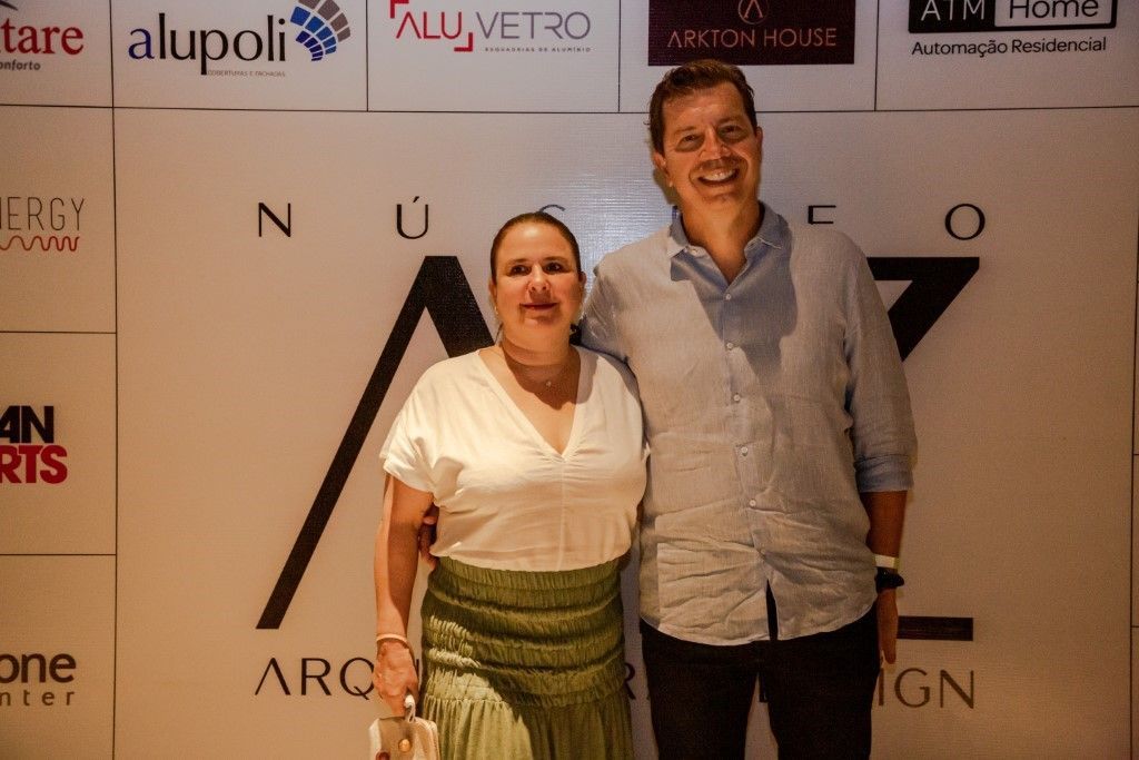 Um homem e uma mulher estão posando para uma foto em frente a uma parede com logotipos.
