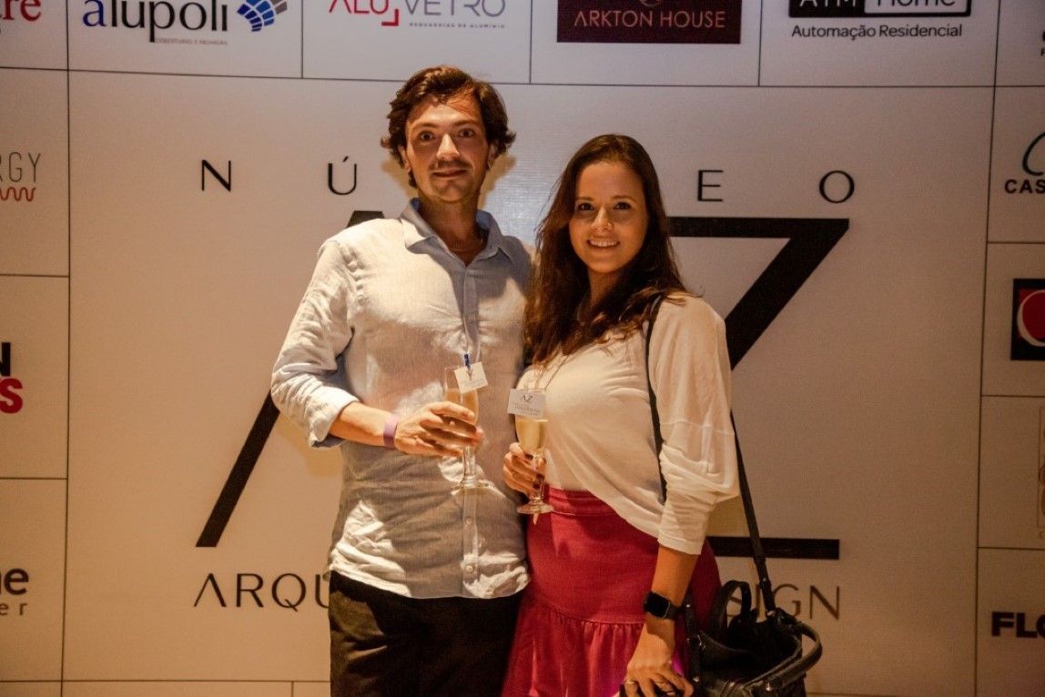 Um homem e uma mulher em pé em frente a uma parede com logotipos