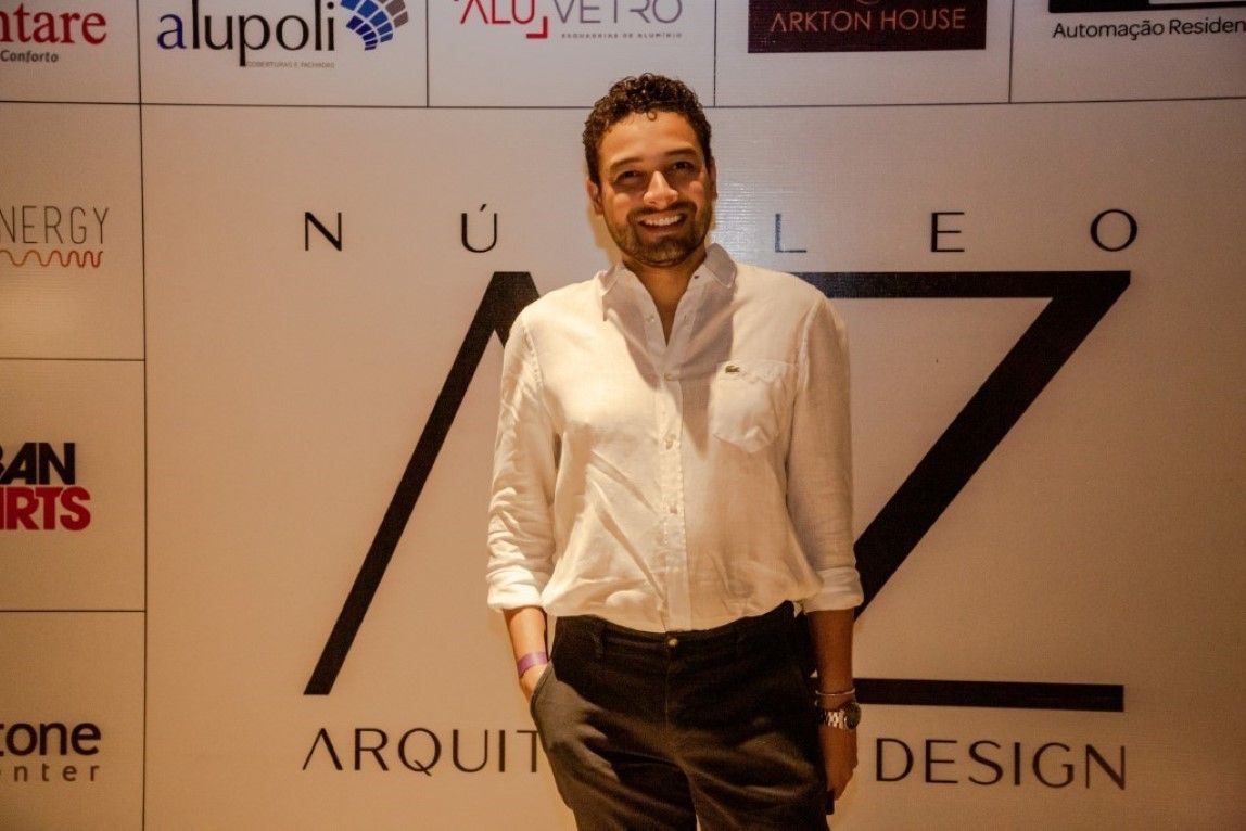 Um homem de camisa branca está parado em frente a uma placa que diz arquit design