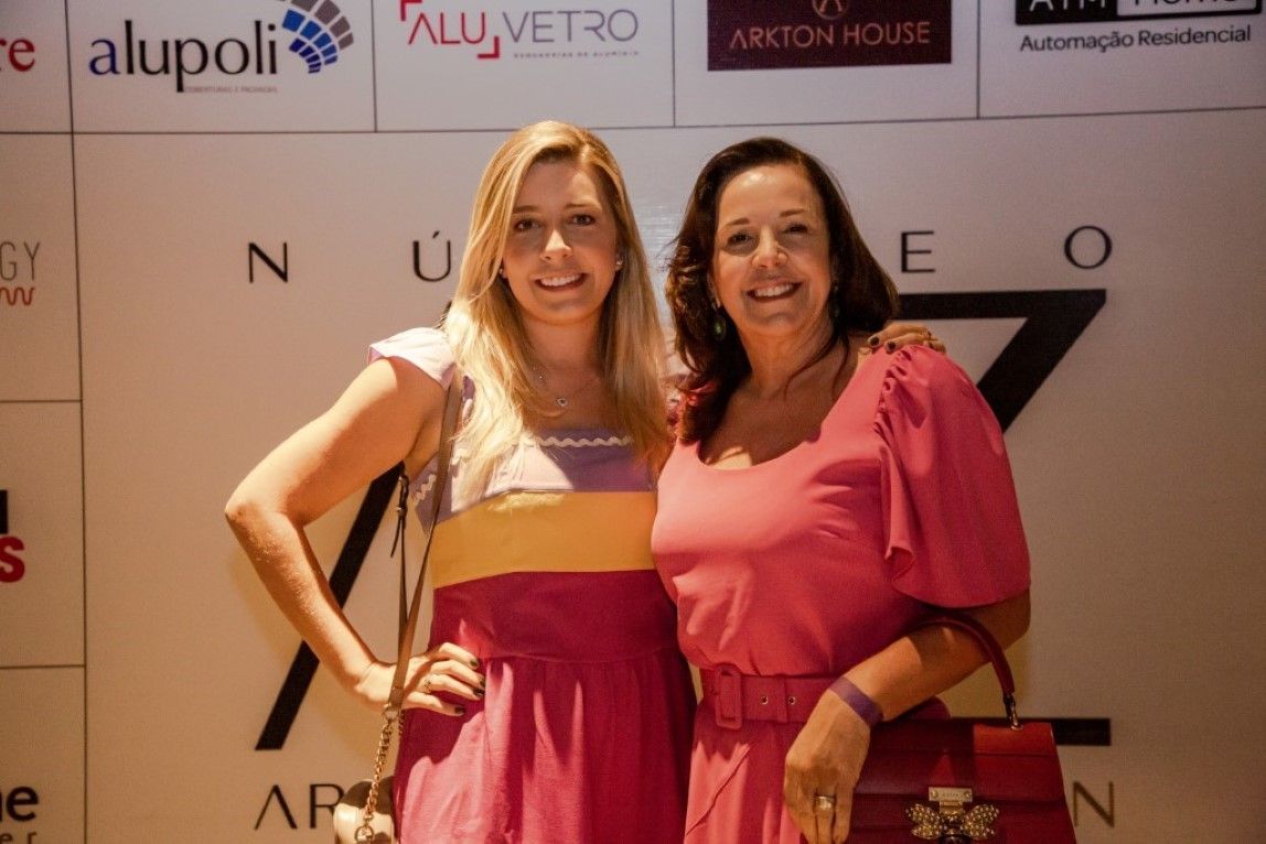 Duas mulheres em vestidos rosa estão posando para uma foto