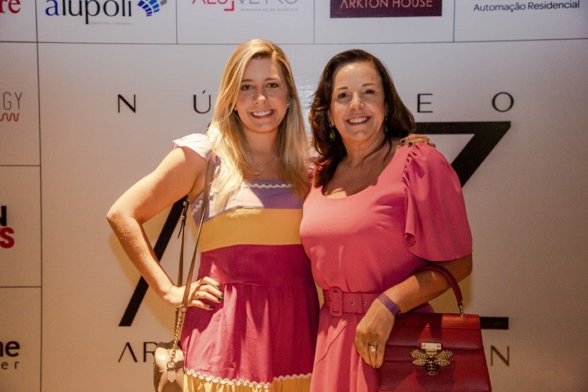 Duas mulheres em vestidos rosa estão posando para uma foto