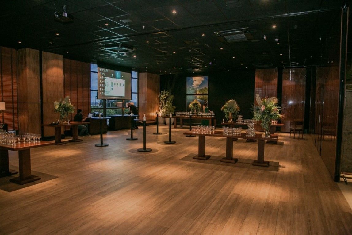 Uma sala grande com piso de madeira, mesas e cadeiras.