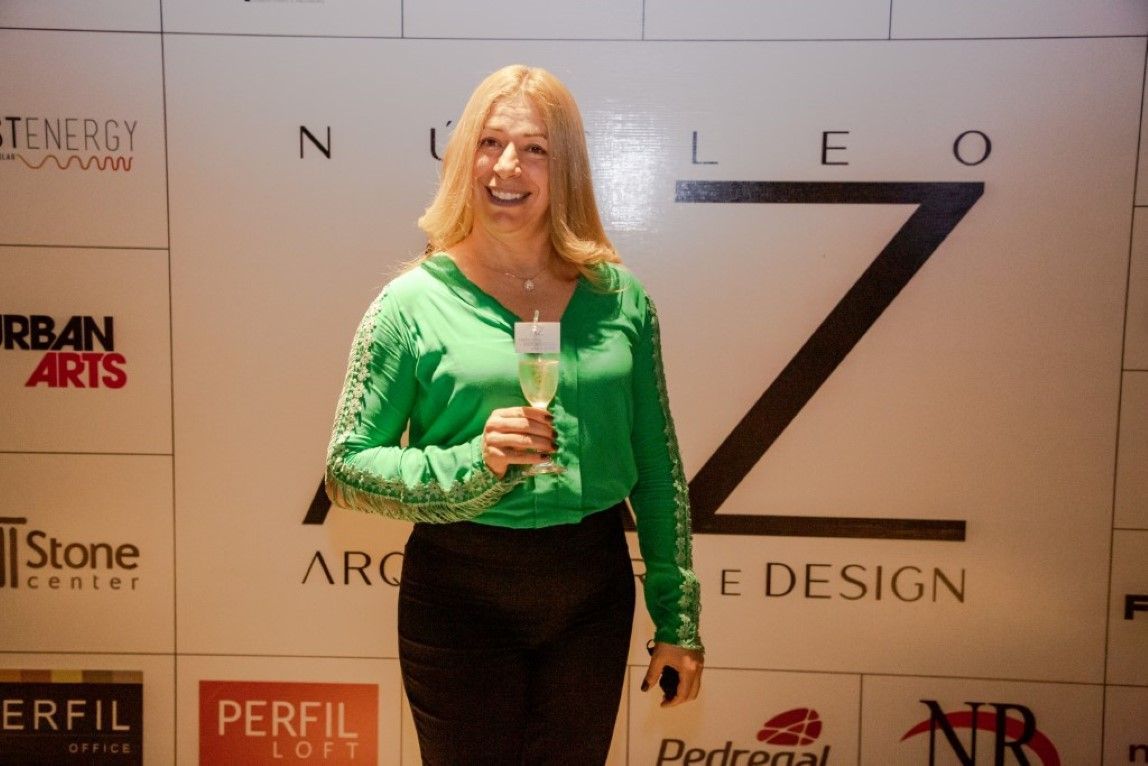Uma mulher de camisa verde está segurando uma taça de champanhe.