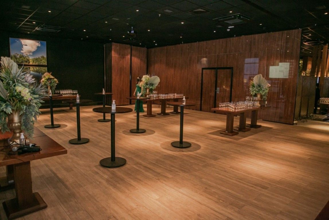 Uma sala grande com piso de madeira e mesas.
