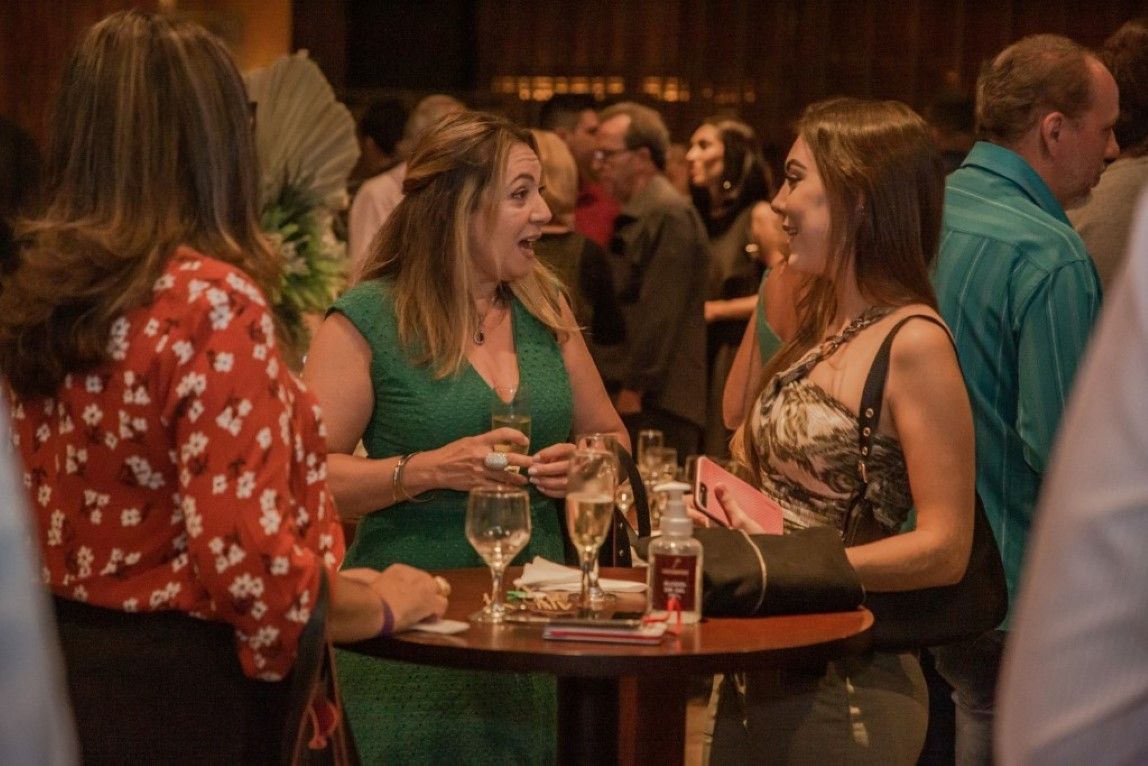 Um grupo de pessoas está sentado ao redor de uma mesa conversando entre si.