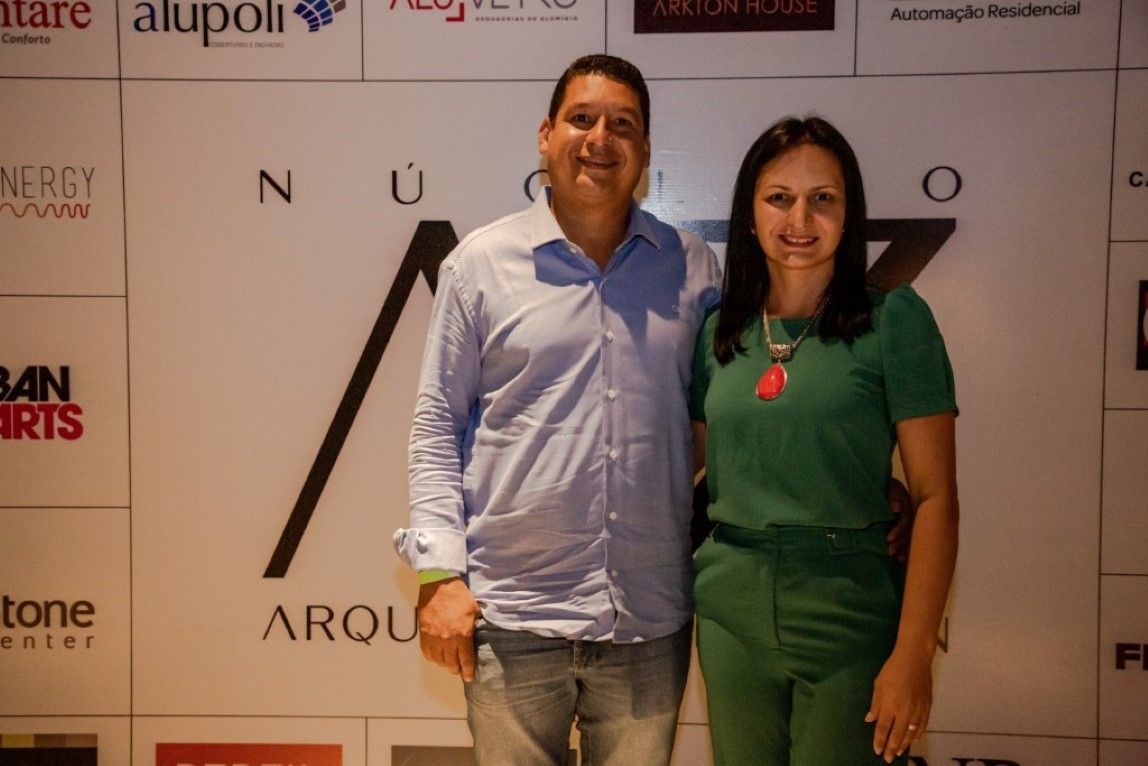 Um homem e uma mulher estão posando para uma foto em frente a uma parede com logotipos.