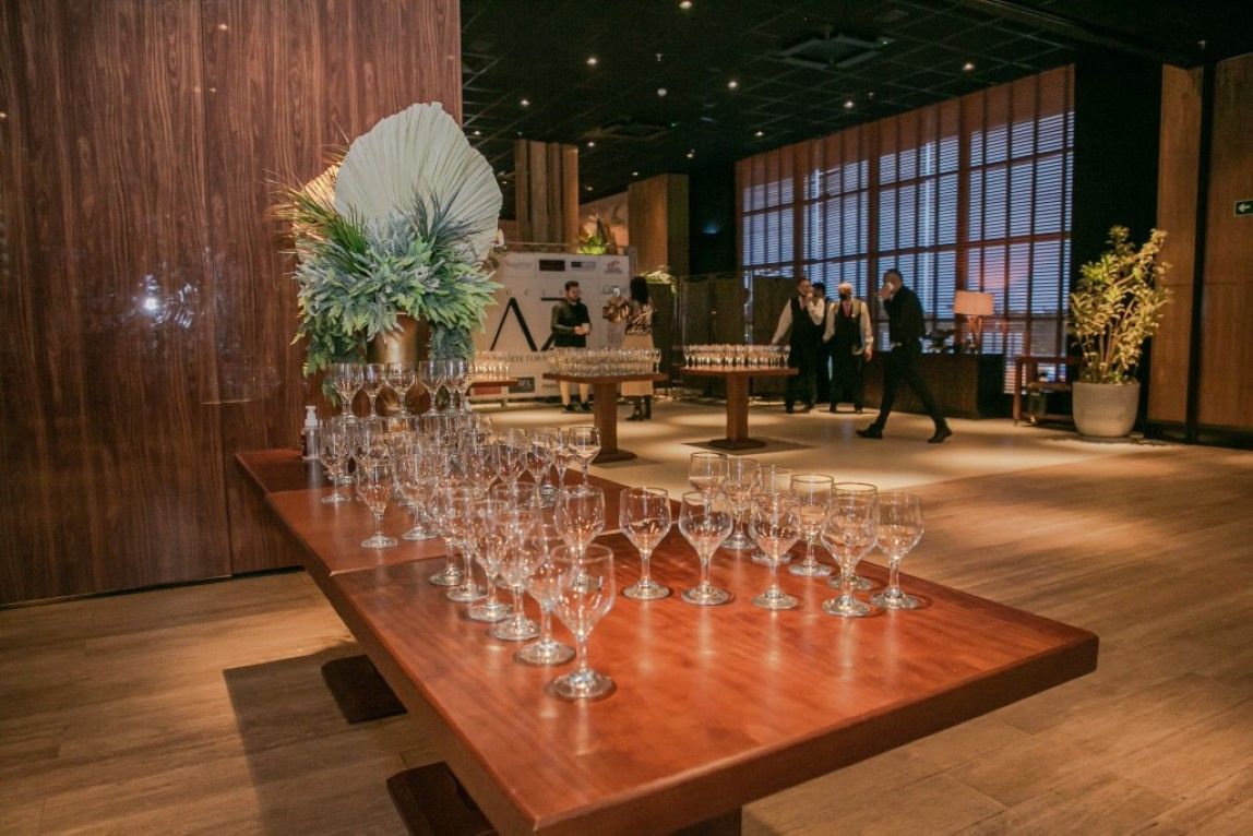 Uma mesa de madeira coberta com muitas taças de vinho em uma sala.