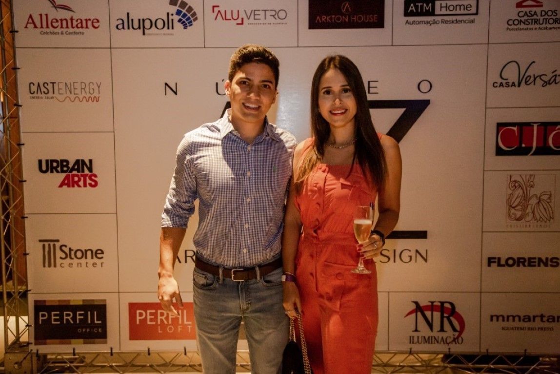 Um homem e uma mulher em pé em frente a uma parede com logotipos