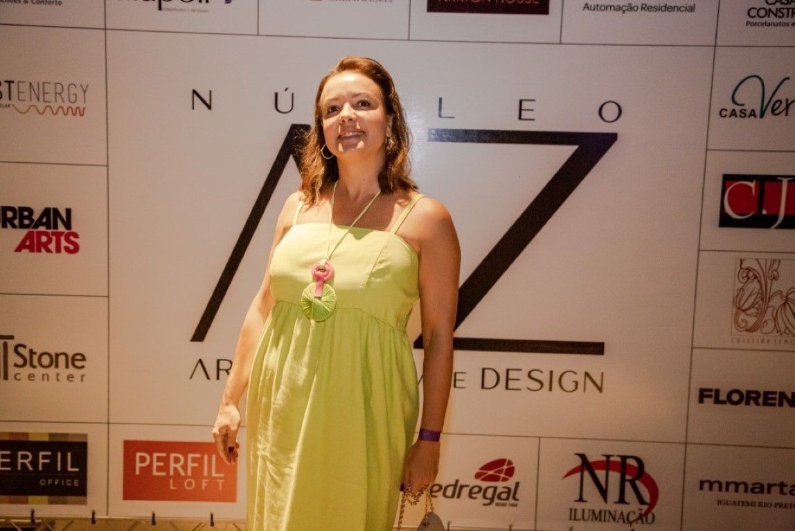 Uma mulher com um vestido verde está parada em frente a uma parede com logotipos