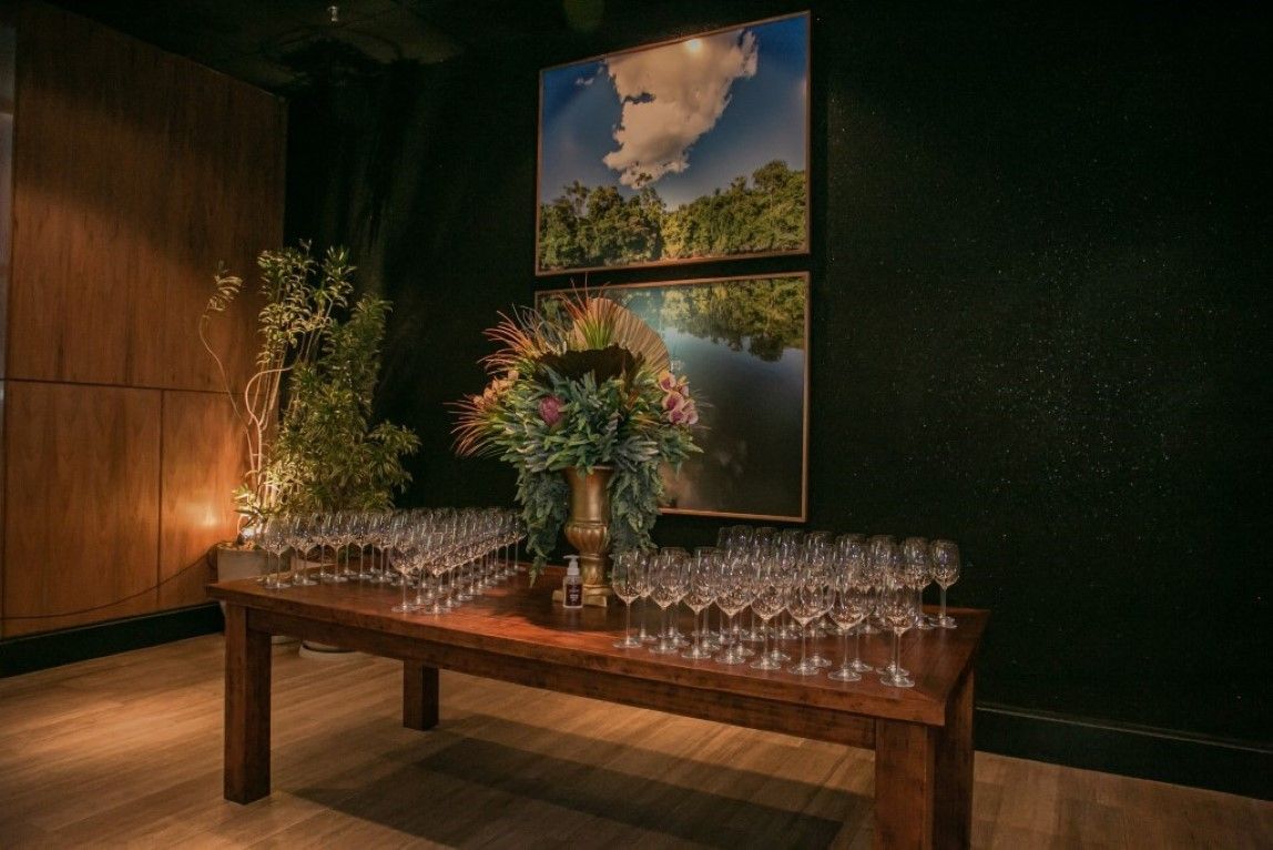 Uma mesa de madeira com um vaso de flores e taças de vinho sobre ela.