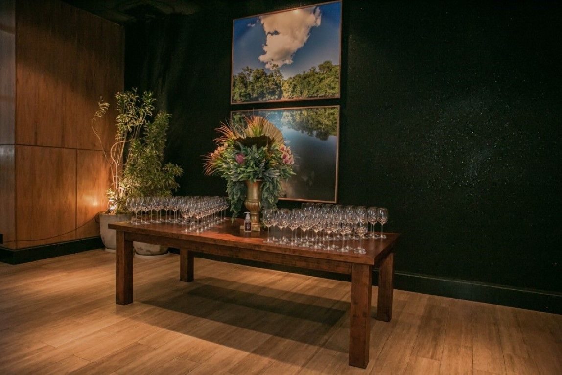 Uma mesa de madeira com um vaso de flores e taças de vinho sobre ela.