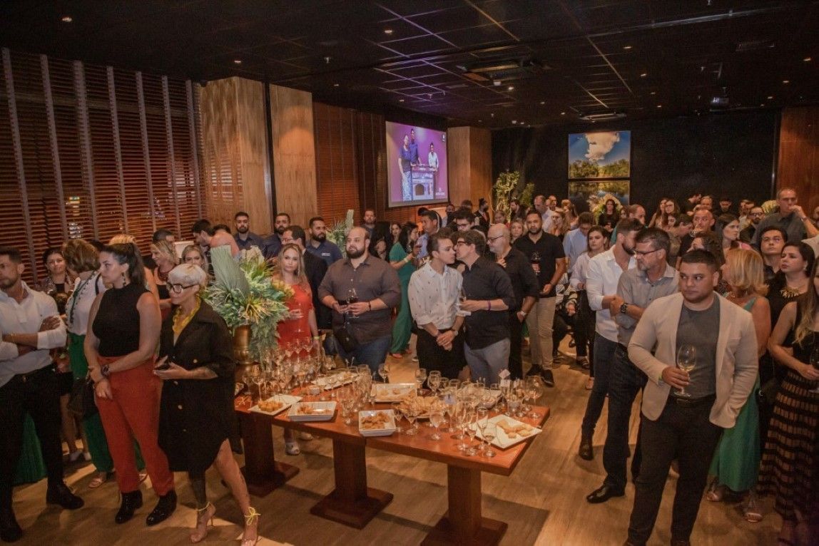 Um grande grupo de pessoas está em pé ao redor de uma mesa em um restaurante.