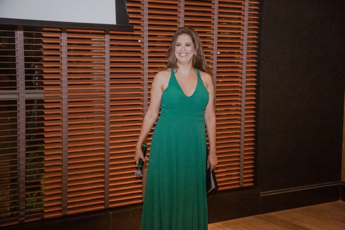 Uma mulher com um vestido verde está parada em frente a uma parede de madeira.
