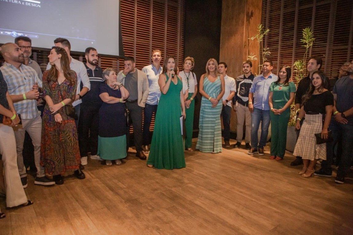 Um grupo de pessoas está em volta de uma mulher com um vestido verde.