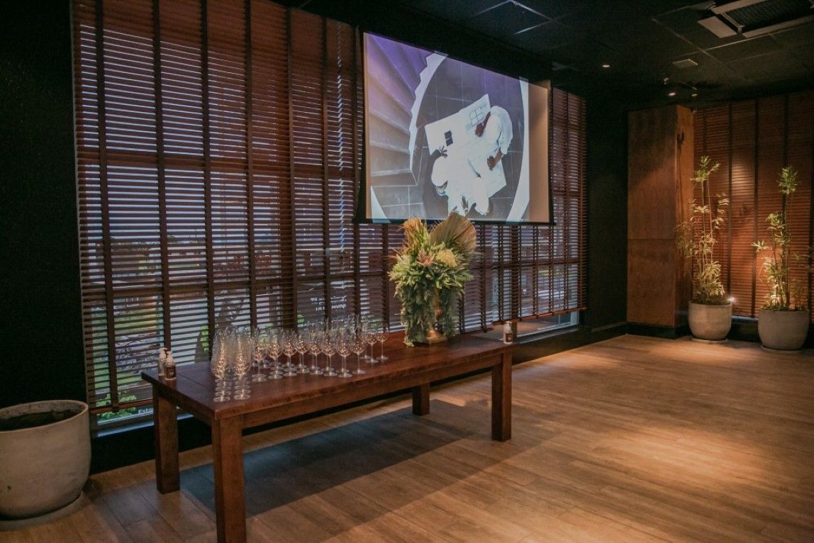 Uma sala com uma tela de projetor e uma mesa com taças de vinho.