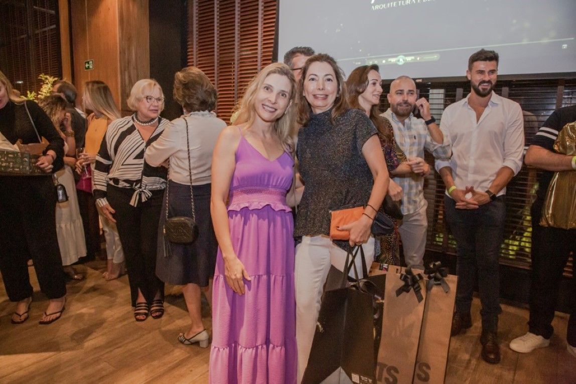 Duas mulheres estão posando para uma foto na frente de uma multidão em uma festa.
