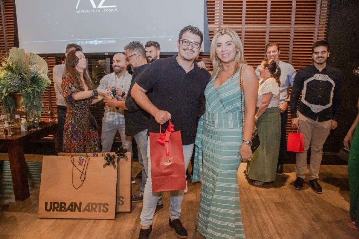 Um homem e uma mulher estão posando para uma foto enquanto seguram uma sacola de presente.
