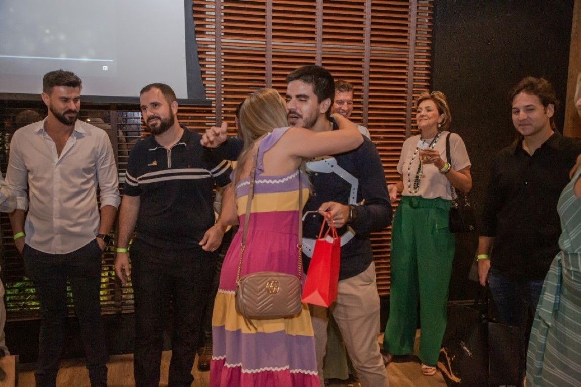 Um grupo de pessoas está em volta de um homem e uma mulher se abraçando.