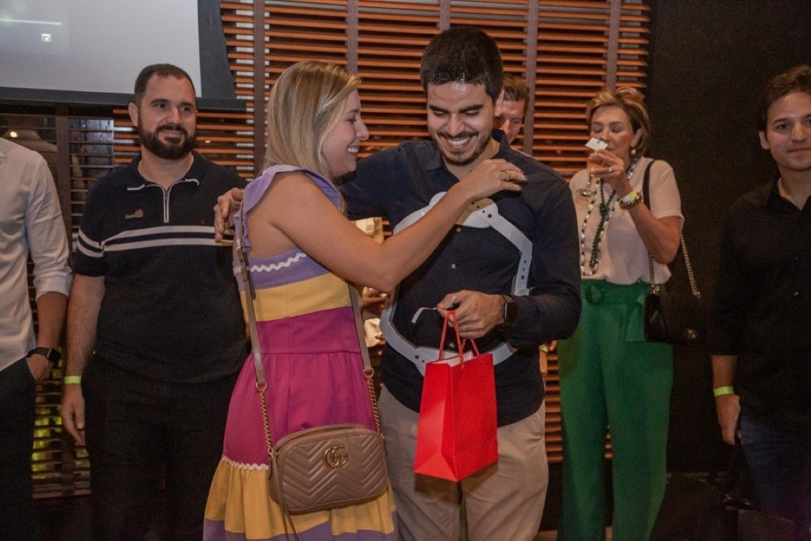 Um grupo de pessoas está em volta de um homem segurando uma sacola vermelha.