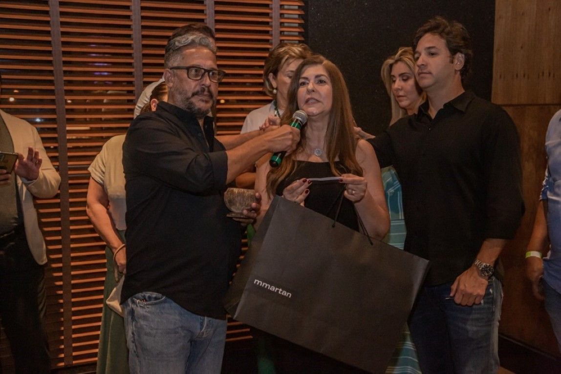Um homem está falando em um microfone enquanto uma mulher segura uma sacola de compras.