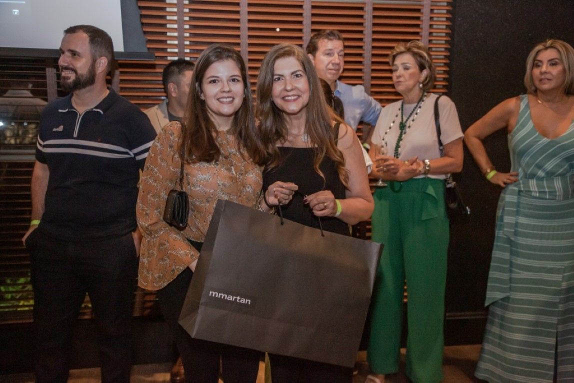 Um grupo de pessoas está em uma sala segurando sacolas de compras.