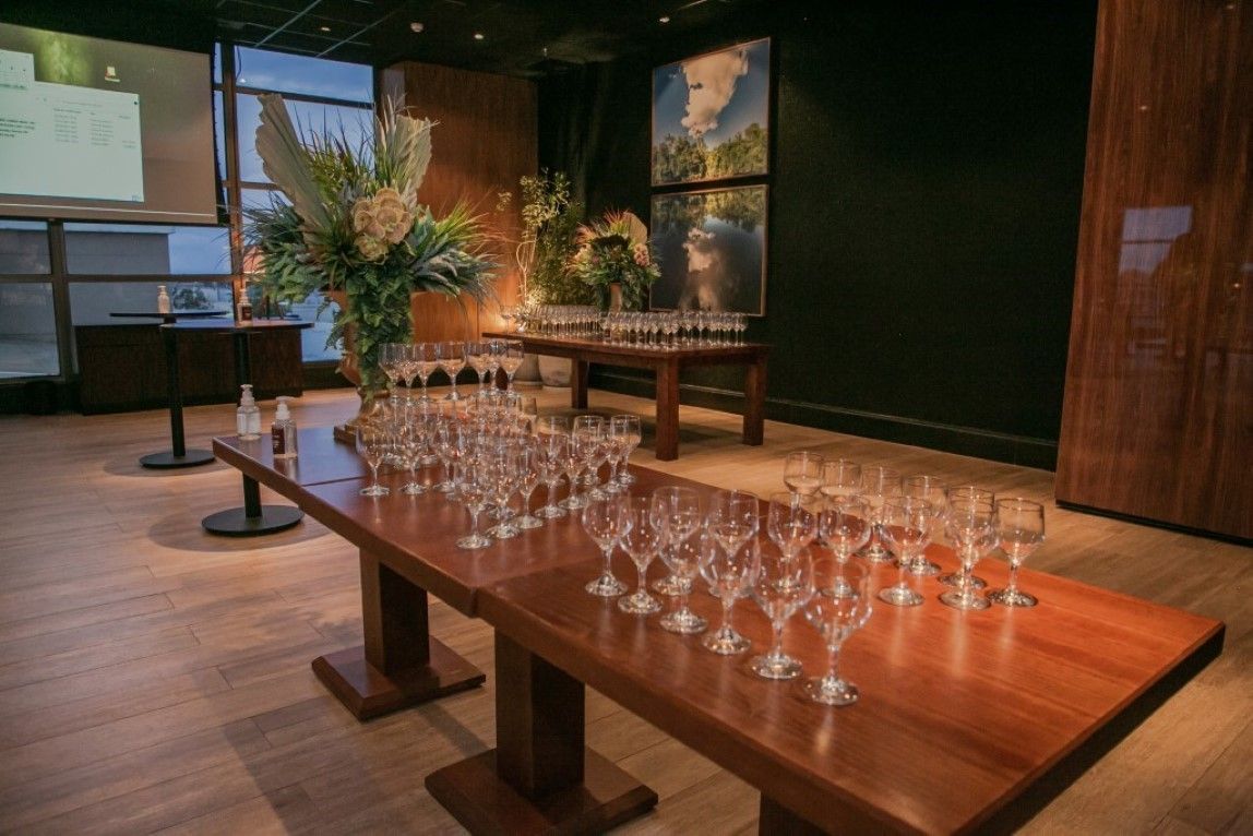 Uma mesa de madeira com muitas taças de vinho em cima dela em uma sala.