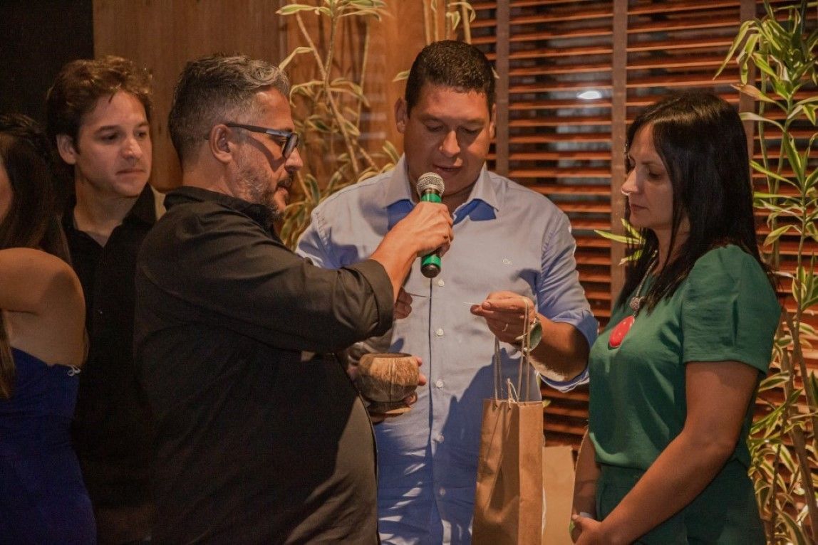Um homem está segurando um microfone na frente de um grupo de pessoas.