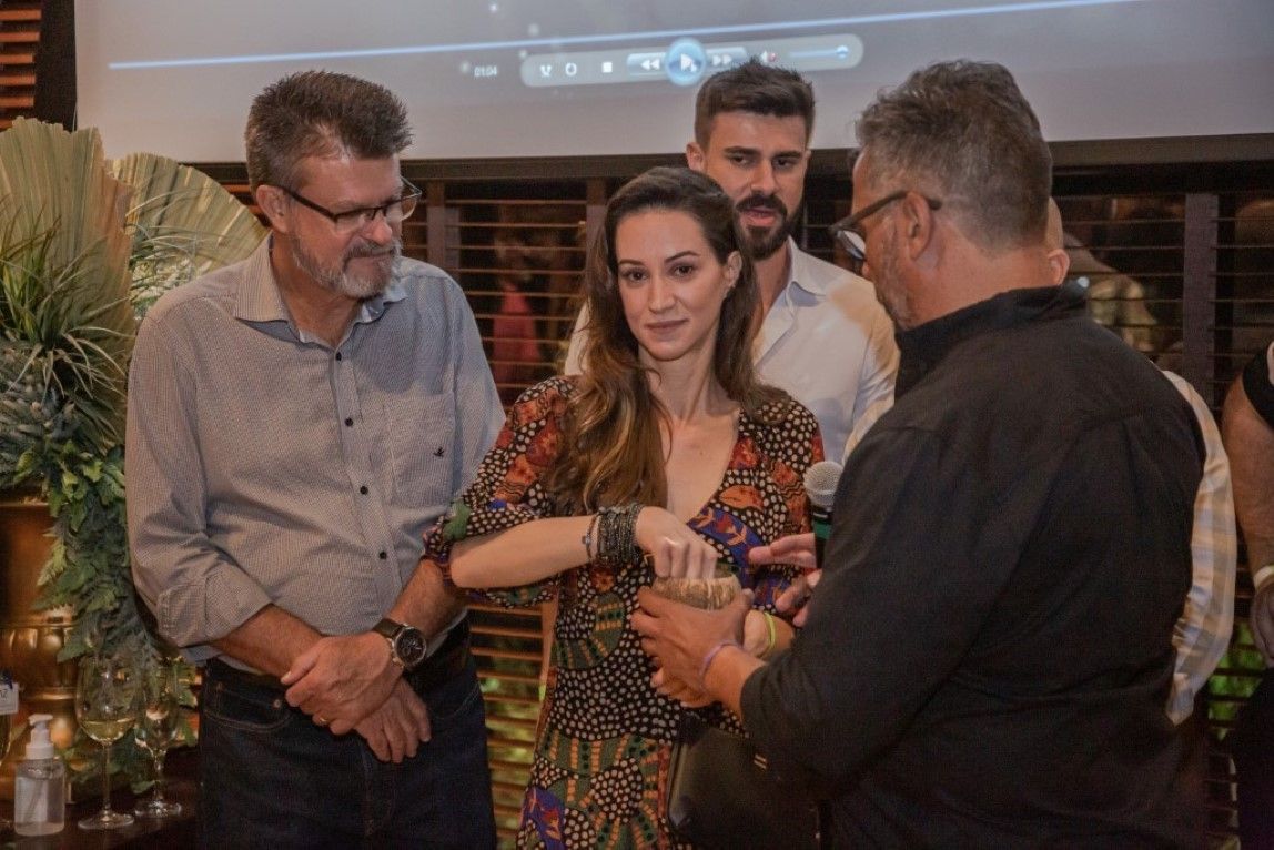 Um grupo de pessoas está em volta de uma mulher segurando um microfone.