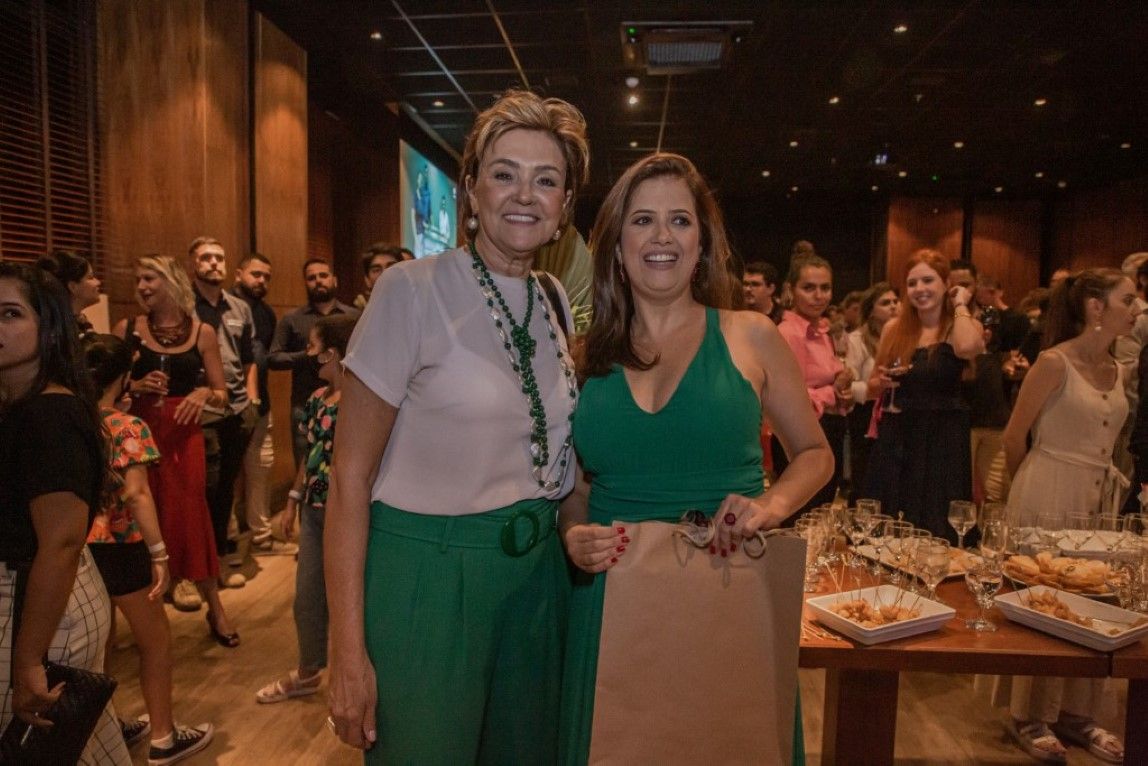 Duas mulheres estão posando para uma foto na frente de uma multidão em uma festa.