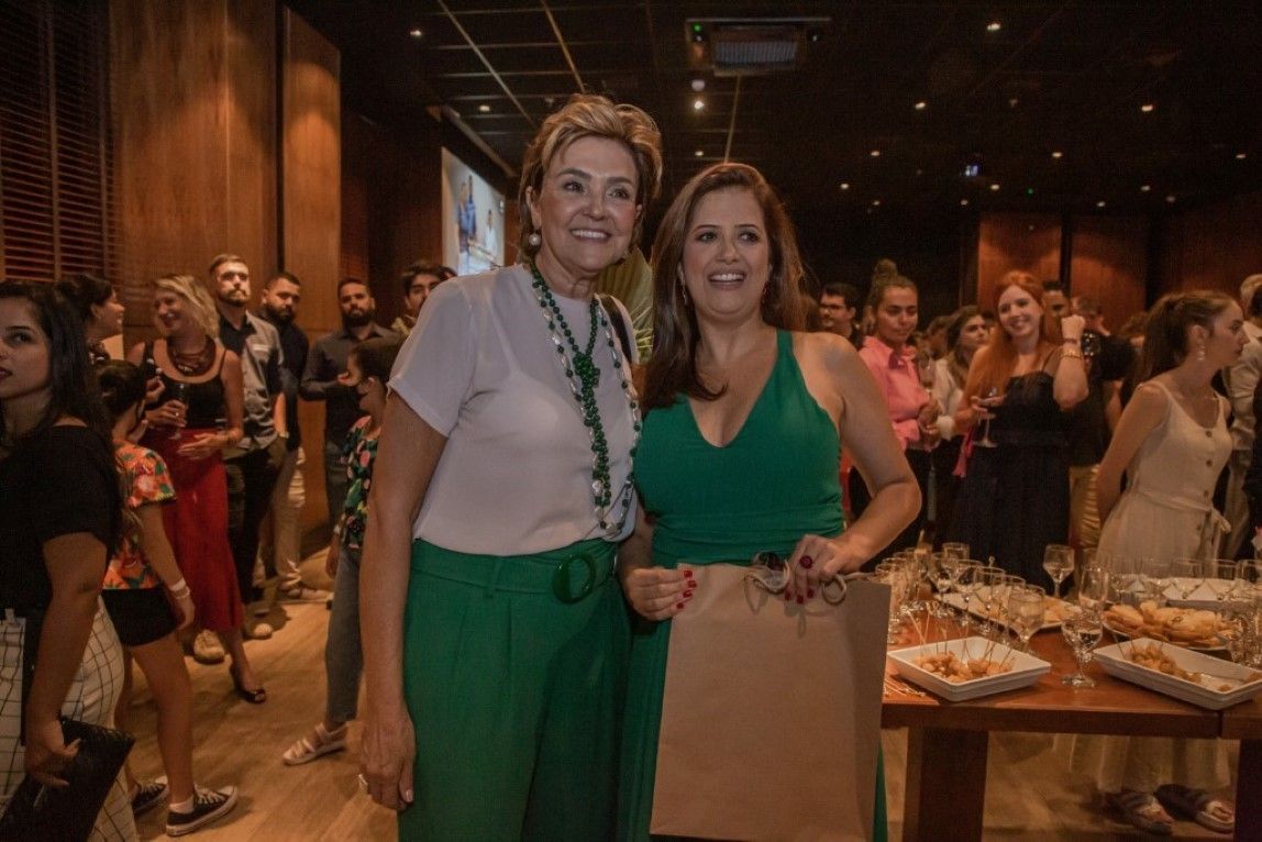 Duas mulheres estão posando para uma foto na frente de uma multidão em uma festa.