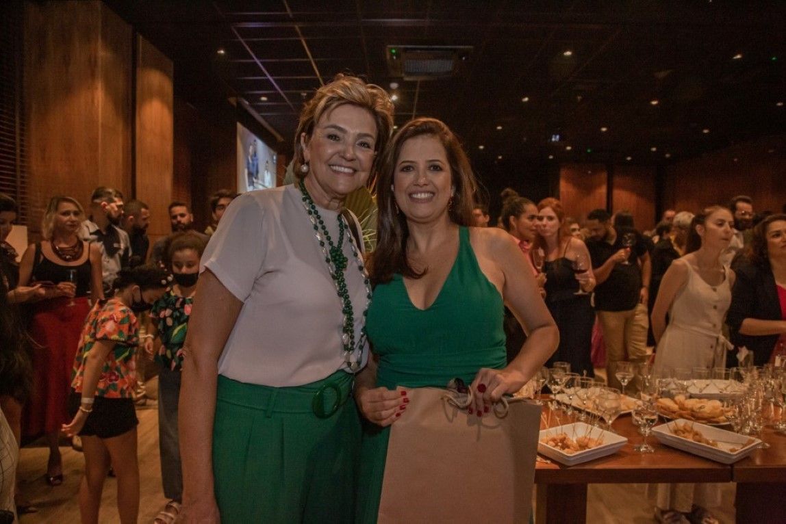 Duas mulheres estão posando para uma foto juntas em uma sala.