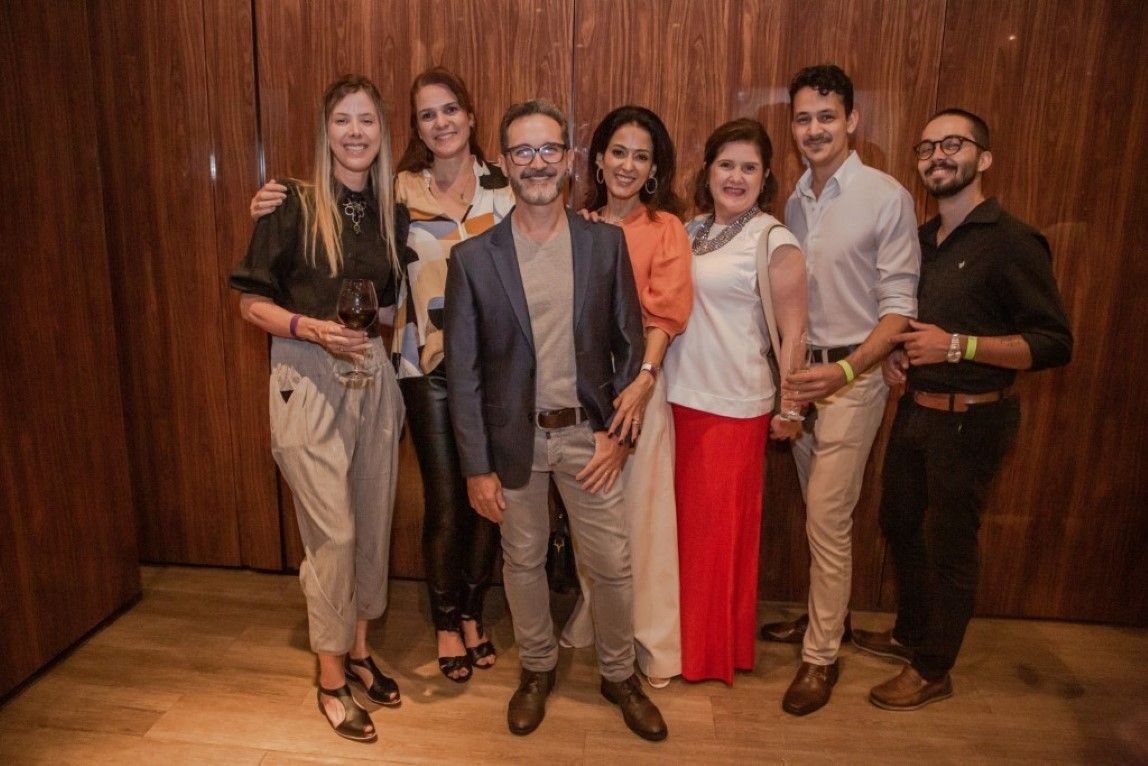 Um grupo de pessoas está posando para uma foto em frente a uma parede de madeira.
